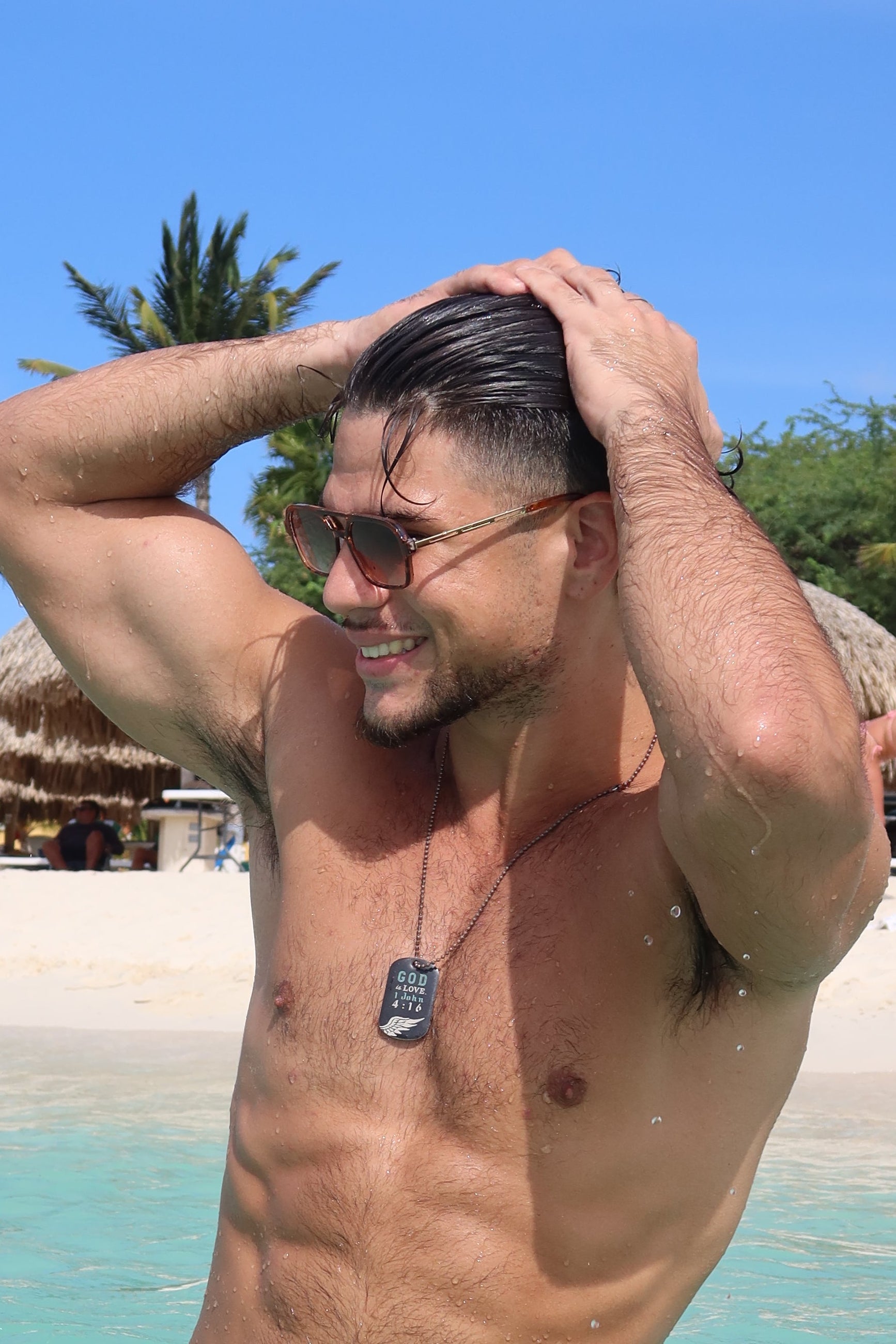 Man relaxing on a beach with palm trees and a clear blue sky.