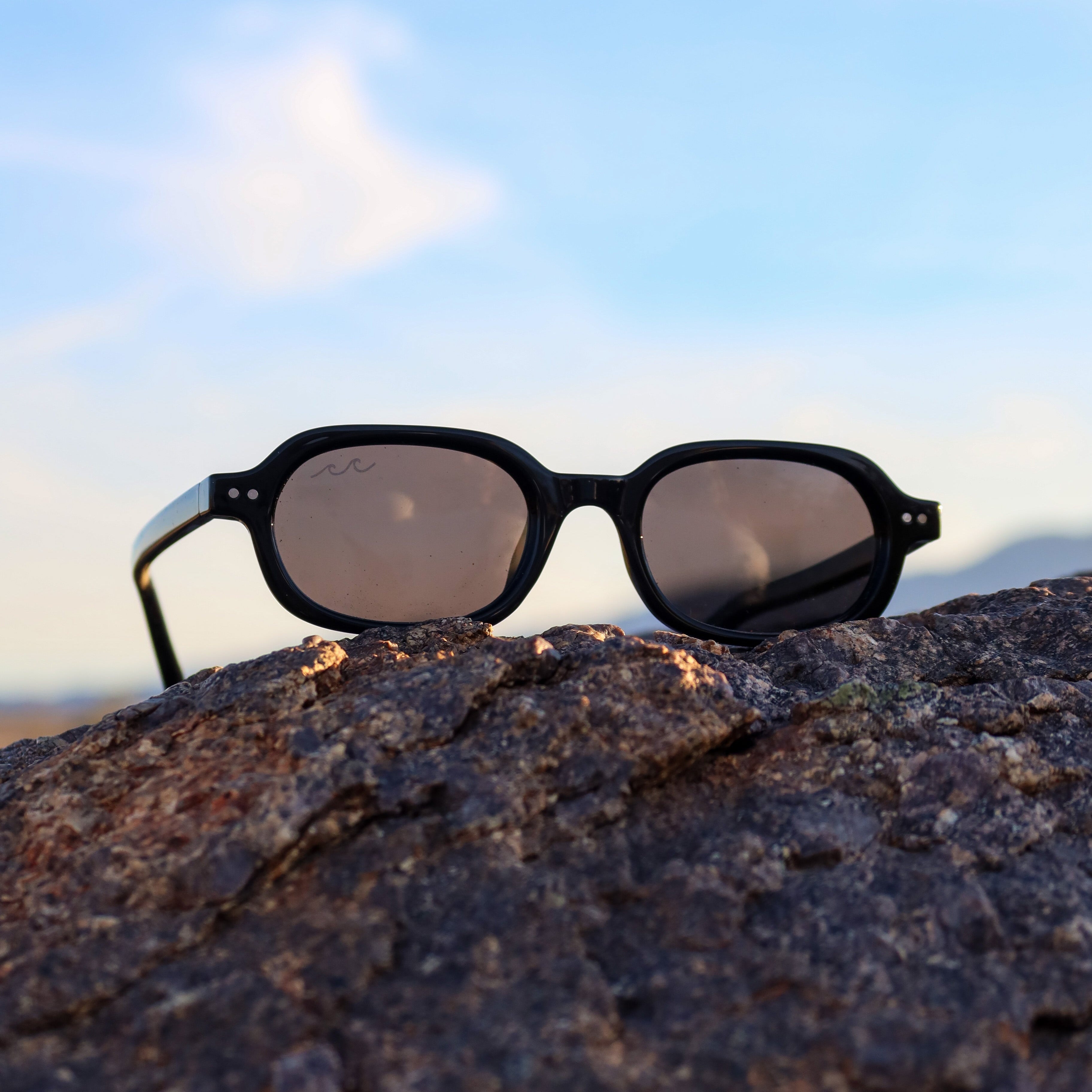 Sunglasses on a rock with a clear sky background