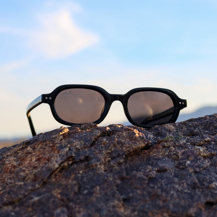 Sunglasses on a rock with a clear sky background