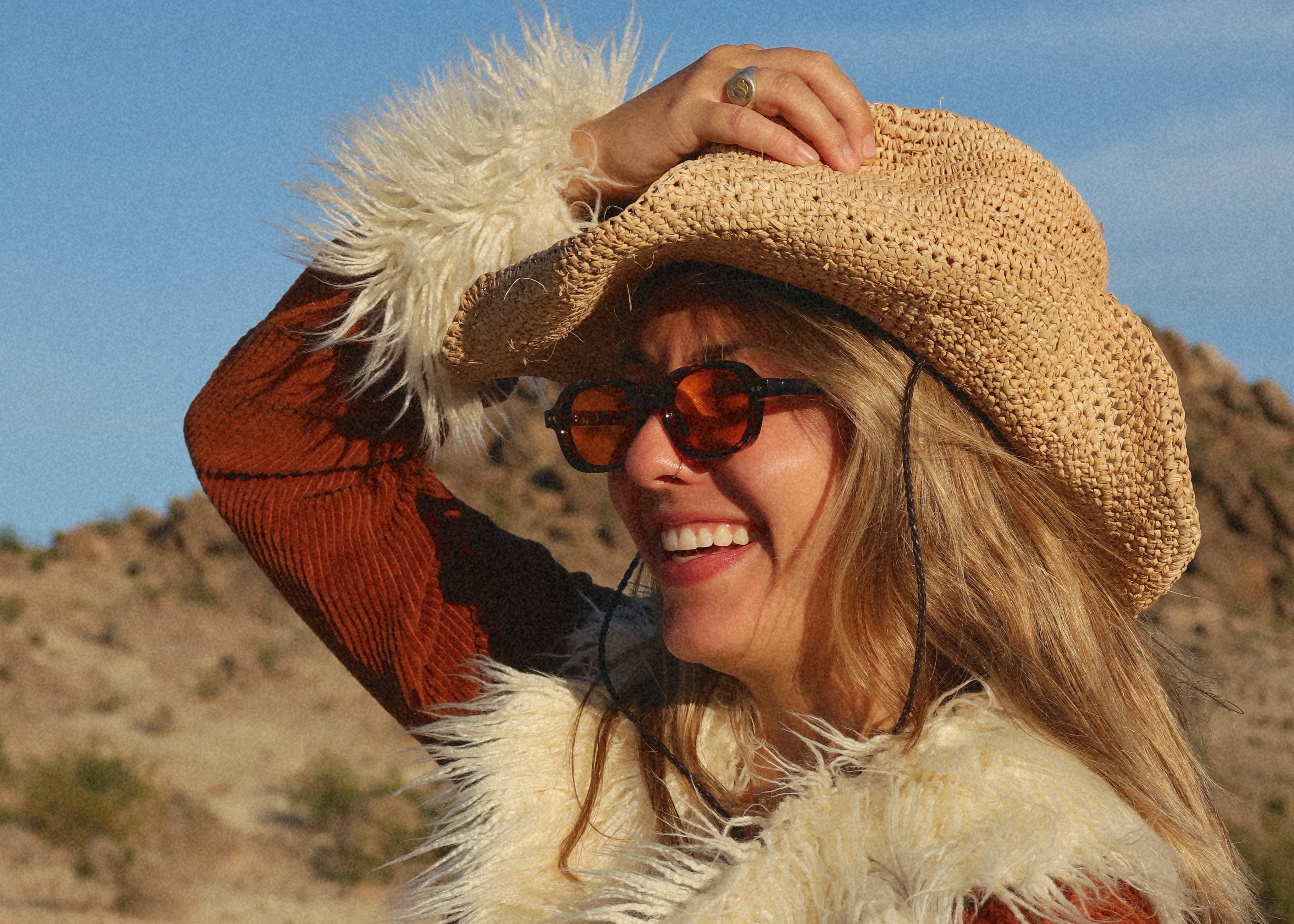 Woman in a cowboy hat and coat with a fur collar in a desert setting