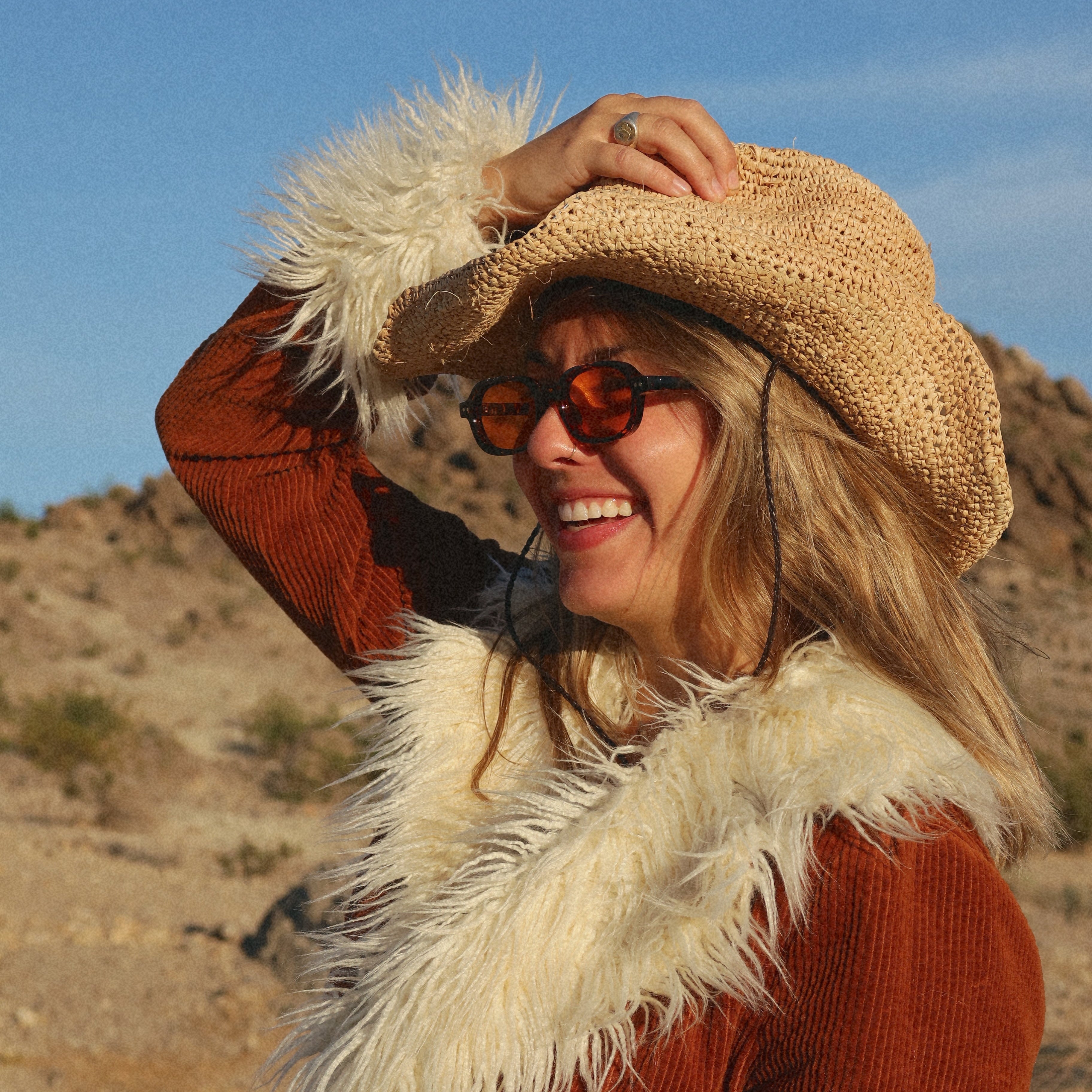 Woman in a cowboy hat and coat with a fur collar in a desert setting