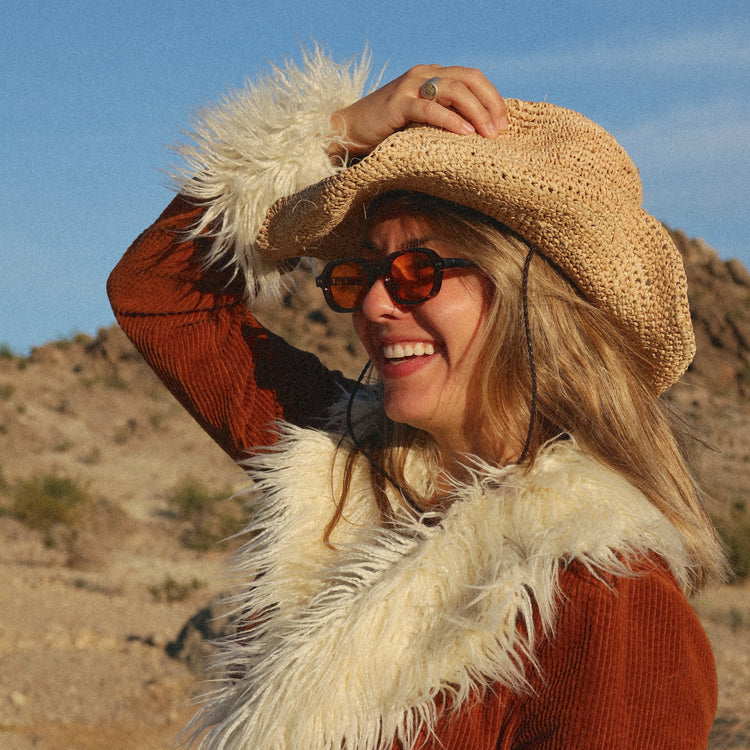 Woman in a cowboy hat and coat with a fur collar in a desert setting