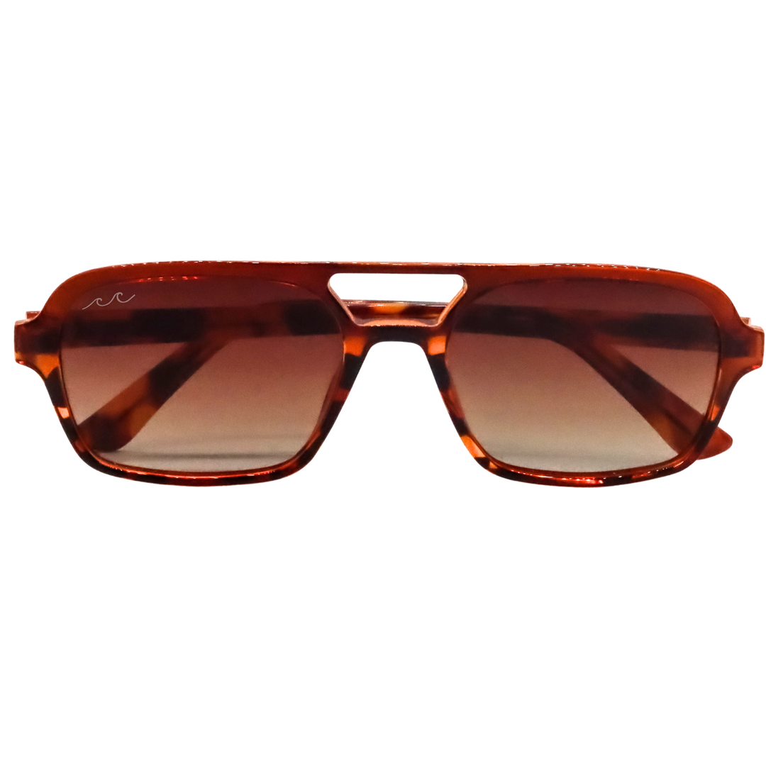 A pair of aviator-style sunglasses with a translucent amber-brown tortoiseshell frame and gradient brown lenses, shown against a plain white background.